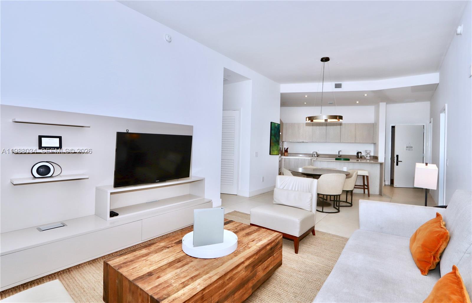 A modern living room features a wooden coffee table, white sofa, and an open kitchen — 4111 S Ocean Dr, Hollywood FL 33019, HOLLYWOOD, FL