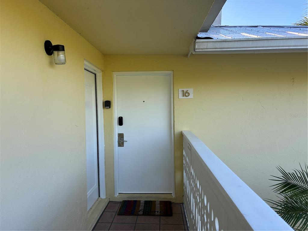 An exterior view shows a white front door labeled 16 with a light fixture above — 5310 GULF OF MEXICO DRIVE UNIT 16, LONGBOAT KEY, FL