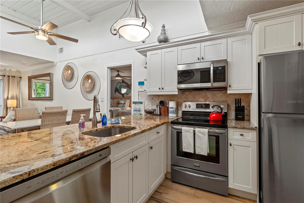 A kitchen features white cabinets, granite countertops, stainless steel appliances, and a breakfast bar — 5310 GULF OF MEXICO DRIVE UNIT 16, LONGBOAT KEY, FL