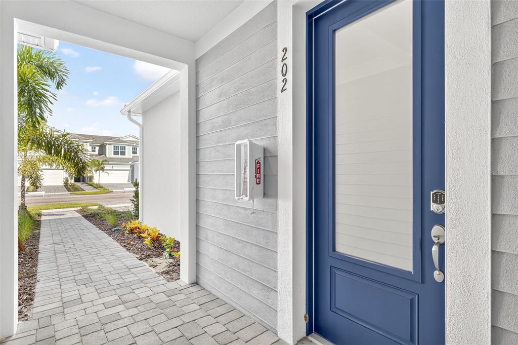 A blue front door with a keypad lock sits next to a wall-mounted fire extinguisher — 17420 MOONFLOWER DRIVE UNIT 202, VENICE, FL