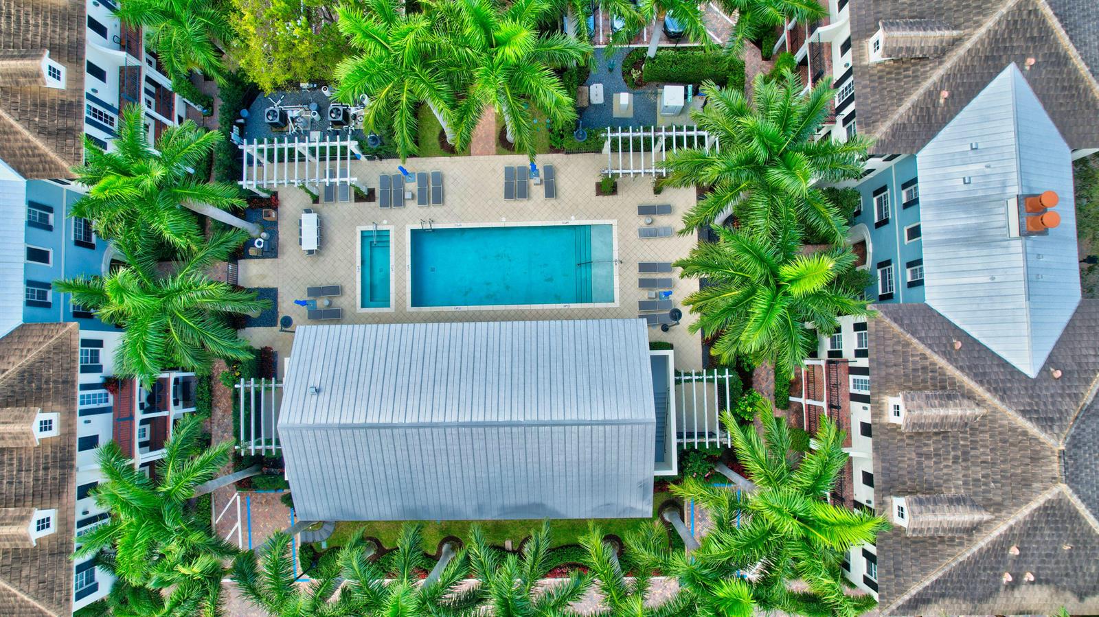 An aerial view shows a swimming pool and patio area surrounded by multi-story residential buildings — 134 Madison Lane, Delray Beach FL 33444, DELRAY BEACH, FL