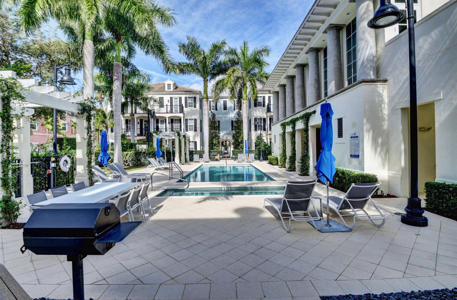 A swimming pool and patio area with lounge chairs, a grill, and palm trees — 134 Madison Lane, Delray Beach FL 33444, DELRAY BEACH, FL