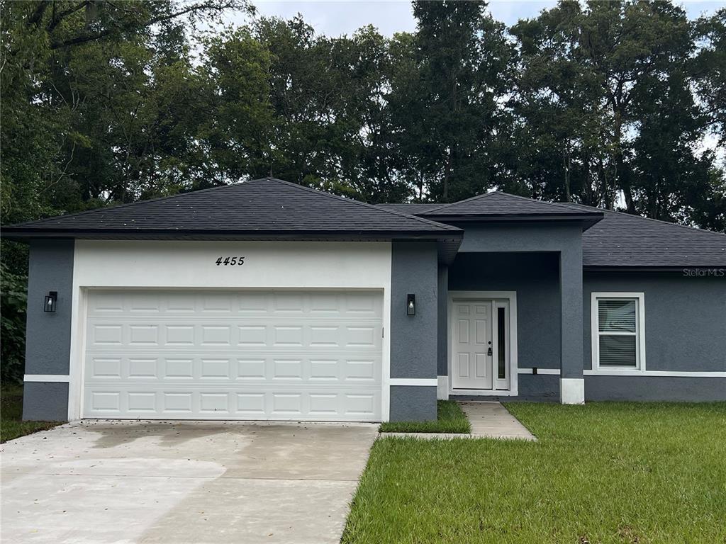 A single-story house features a gray stucco exterior, a white garage door, and a front entrance — 4455 SE 24TH STREET, OCALA, FL