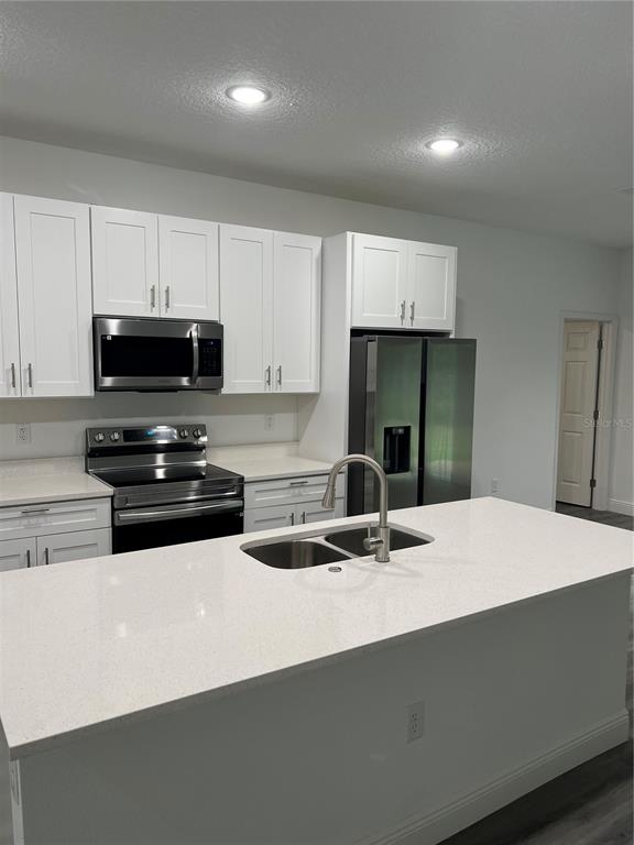 A kitchen features white cabinets, stainless steel appliances, and a large quartz-topped island — 4455 SE 24TH STREET, OCALA, FL