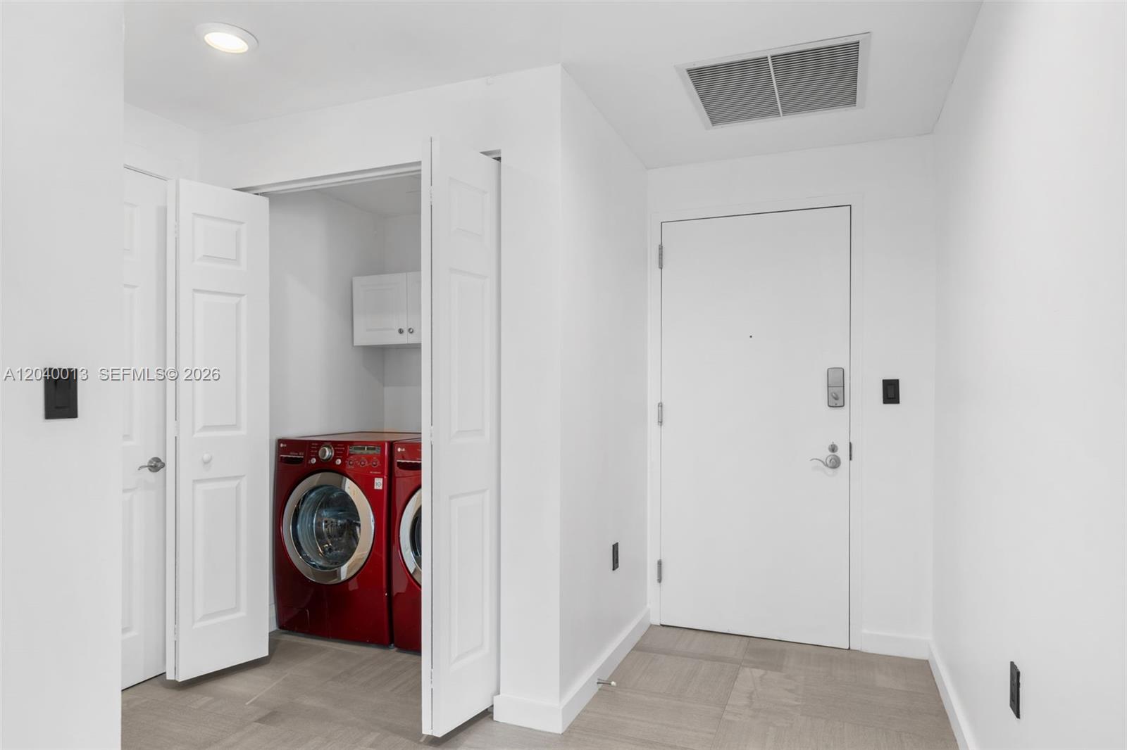 A laundry closet with red appliances sits next to a white door in a room — 1745 E Hallandale Beach Blvd, Hallandale Beach FL 33009, HALLANDALE BEACH, FL