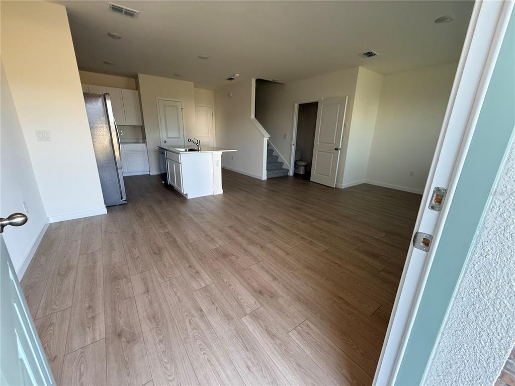 An open-concept kitchen and living area features light wood-look flooring and white cabinetry — 599 PRESTON COVE DRIVE, ST CLOUD, FL