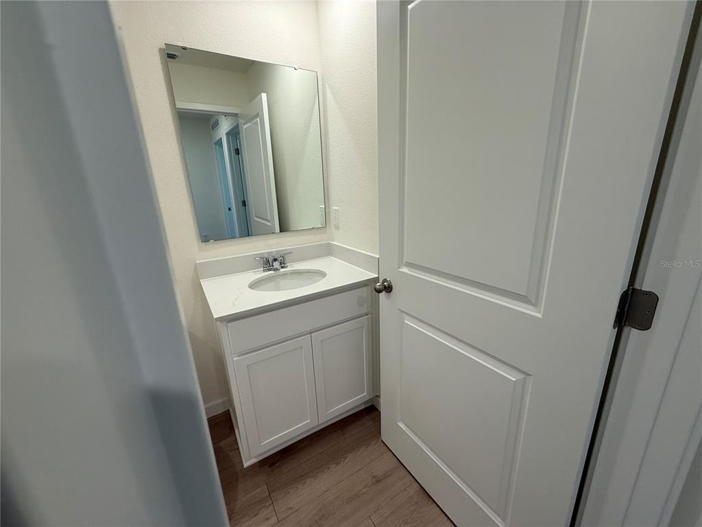 A small bathroom features a white vanity with a sink, a mirror, and wood-look flooring — 599 PRESTON COVE DRIVE, ST CLOUD, FL