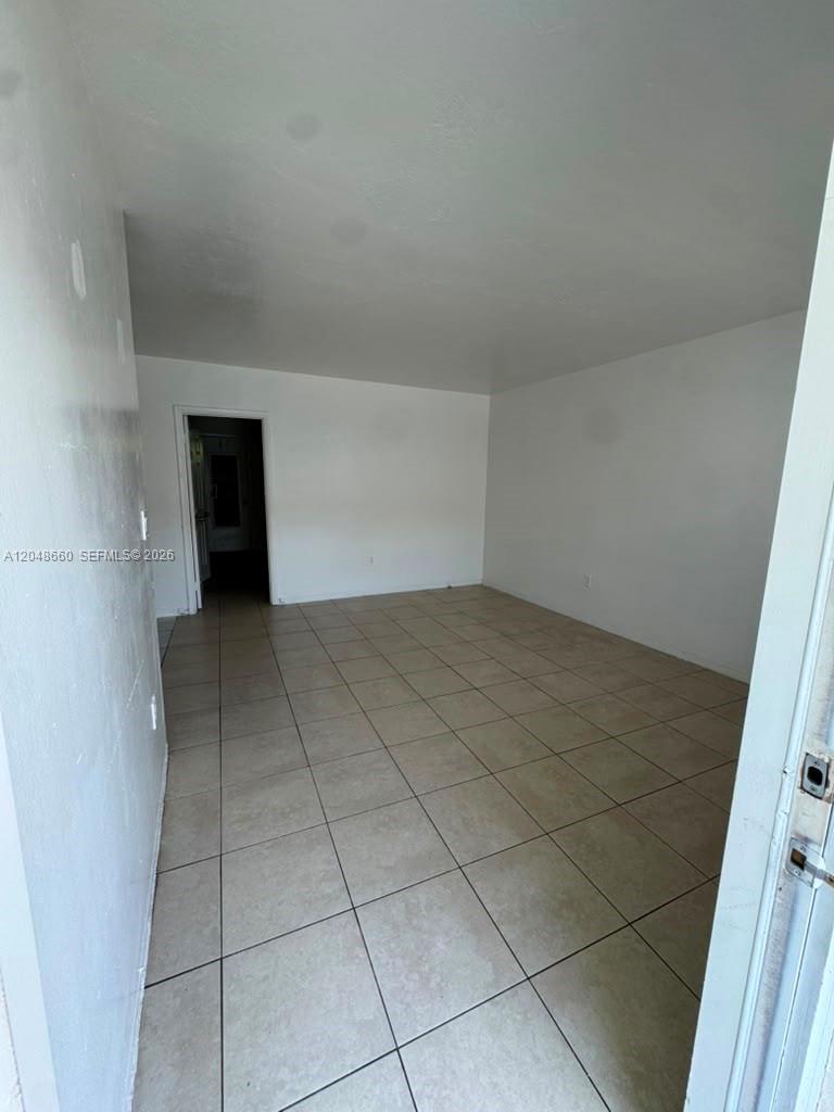 An empty room features white walls and light-colored square floor tiles — 16001 NE 18th Pl # 3, North Miami Beach FL 33162, NORTH MIAMI BEACH, FL