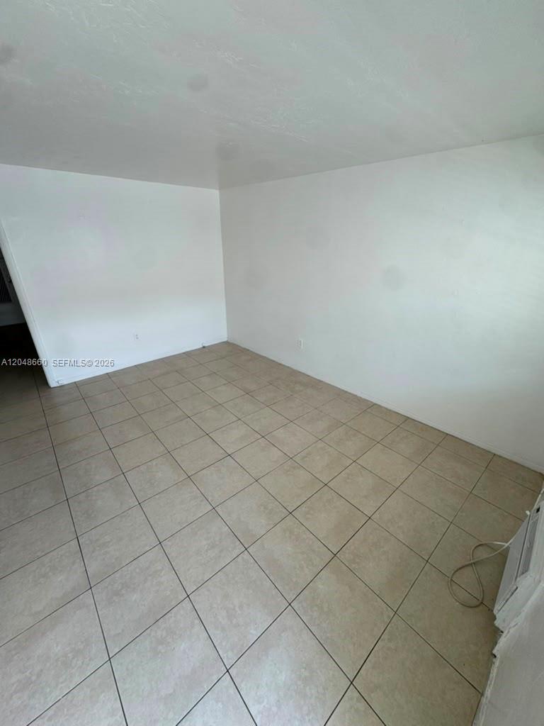 An empty room features light-colored walls and beige tiled flooring — 16001 NE 18th Pl # 3, North Miami Beach FL 33162, NORTH MIAMI BEACH, FL