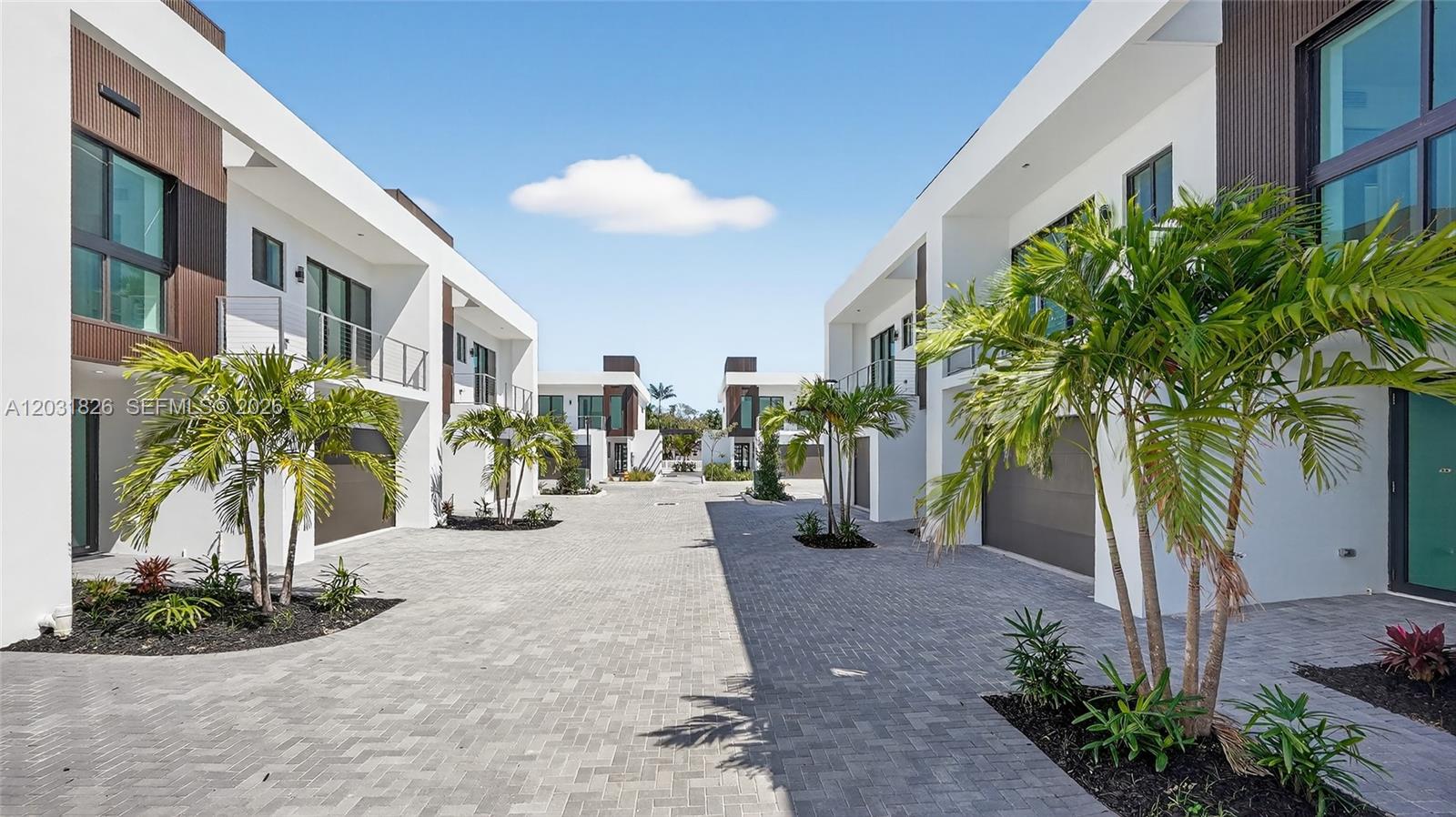 A paved driveway leads between two rows of modern, white multi-story townhomes with palm trees — 4656 SW 32nd Ave # B1, Dania Beach FL 33312, DANIA BEACH, FL