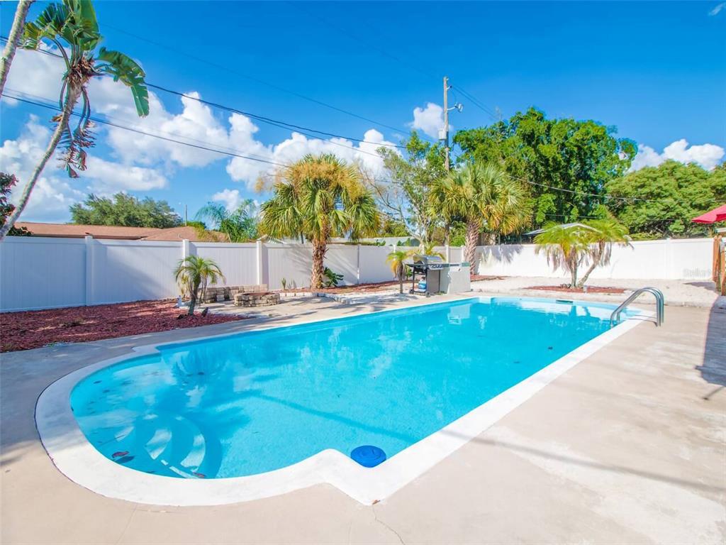 A rectangular swimming pool with a concrete deck sits in a fenced backyard with palm trees — 4401 LENMORE STREET, ORLANDO, FL