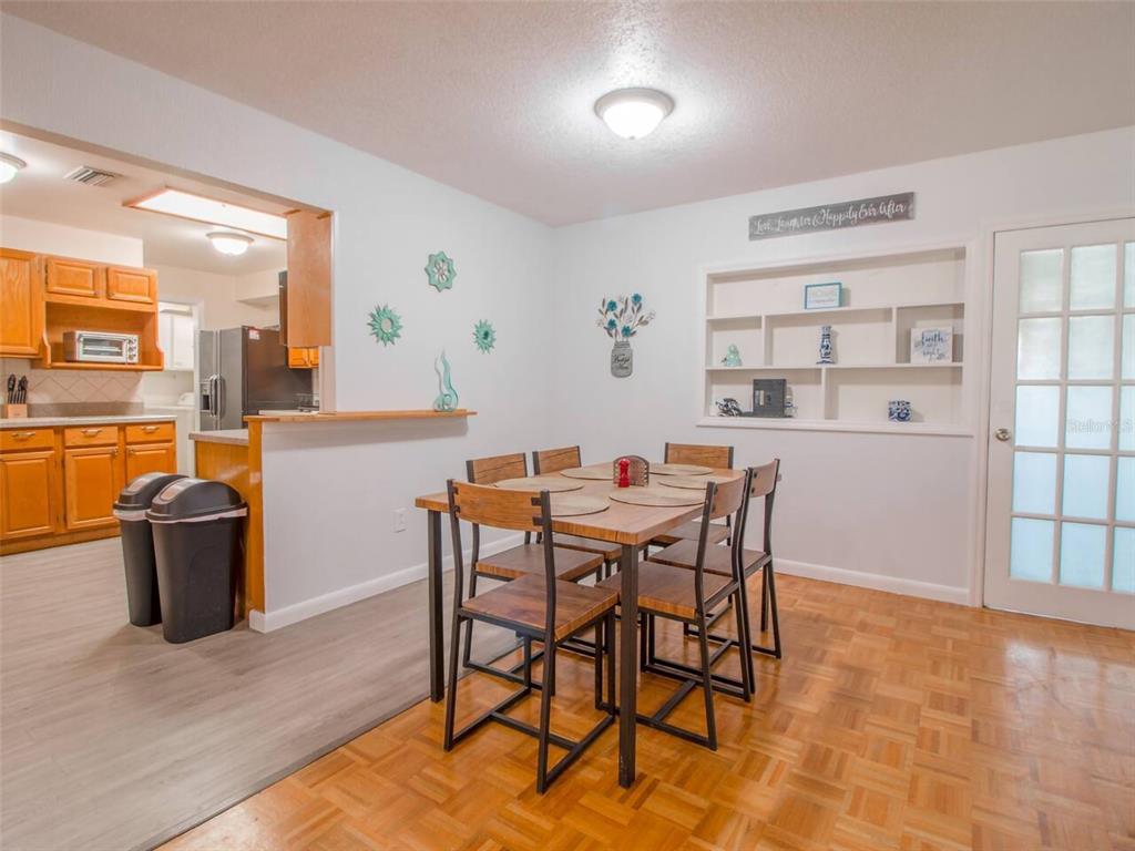 A dining area with a wooden table, chairs, built-in shelving, and parquet flooring — 4401 LENMORE STREET, ORLANDO, FL