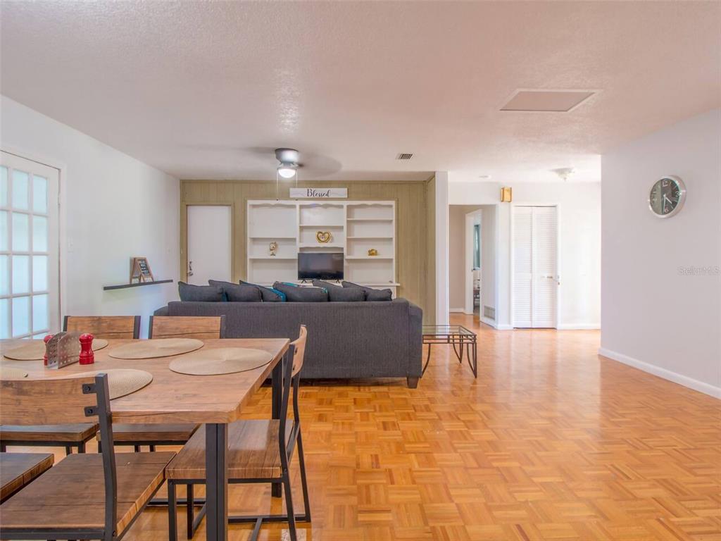 A dining area with a wooden table leads into a living room with built-in shelving — 4401 LENMORE STREET, ORLANDO, FL