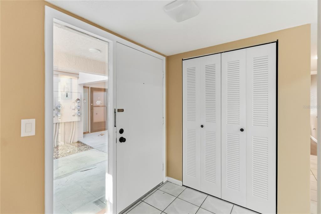 An entryway features a white front door with a sidelight, louvered closet doors, and tile flooring — 164 PERIMETER DRIVE UNIT 4A, DELTONA, FL