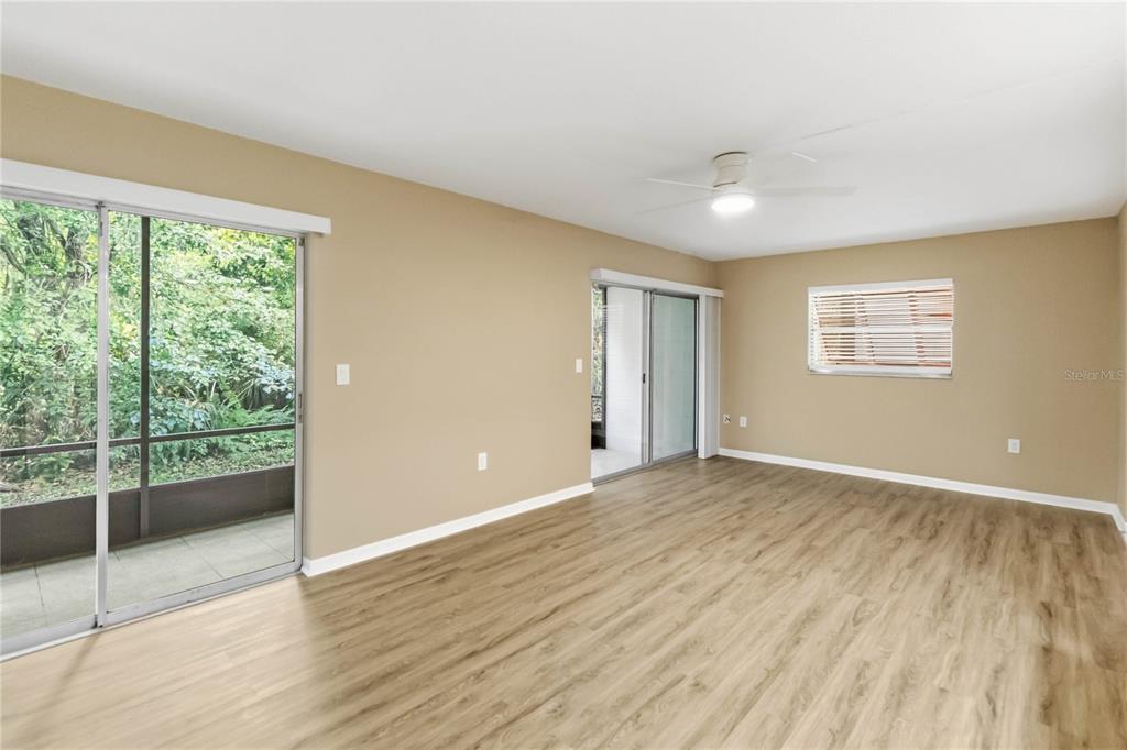 An empty room with light wood-look flooring, beige walls, a ceiling fan, and sliding glass doors — 164 PERIMETER DRIVE UNIT 4A, DELTONA, FL