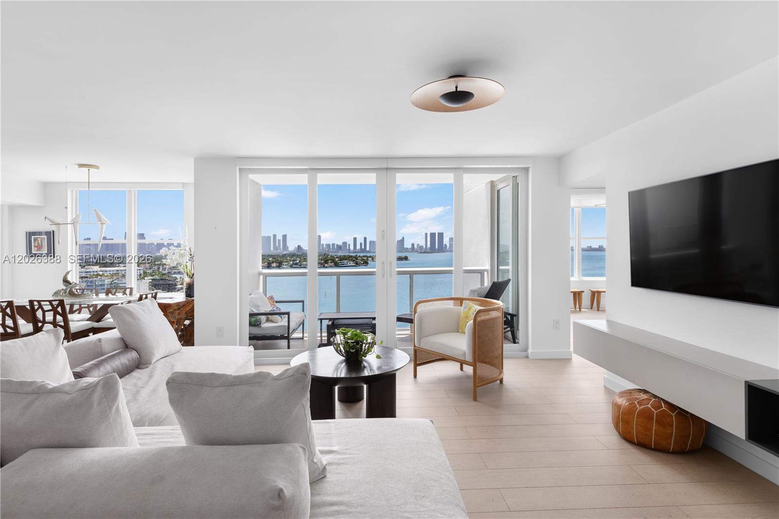 A modern living room features light wood floors, a white sectional, and floor-to-ceiling balcony views — 1800 Sunset Harbour # 1612, Miami Beach FL 33139, MIAMI BEACH, FL