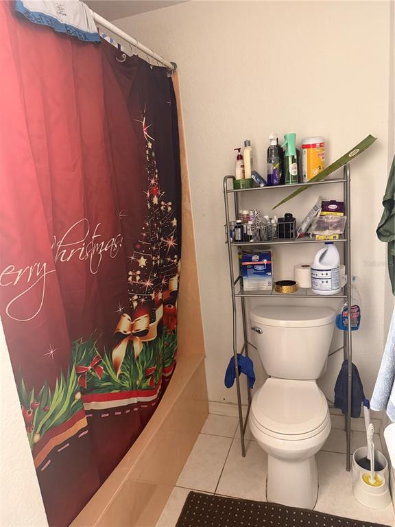 A bathroom features a Christmas-themed shower curtain, a white toilet, and a metal storage rack — 2135 SW 156TH PLACE, OCALA, FL