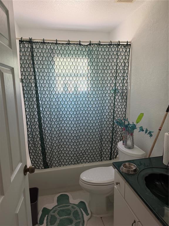 A bathroom featuring a patterned shower curtain, a white toilet, and a dark green vanity countertop — 2135 SW 156TH PLACE, OCALA, FL