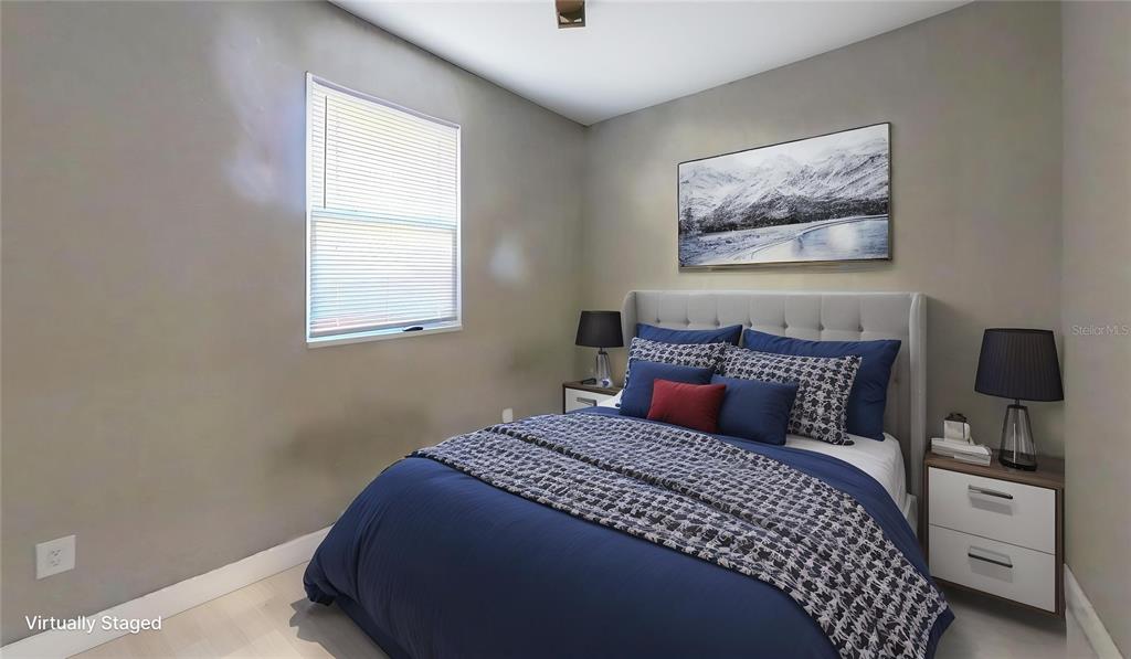 A bedroom features a bed with blue bedding, two nightstands with lamps, and wall art — 2726 MIAMI TERRACE UNIT B, KISSIMMEE, FL