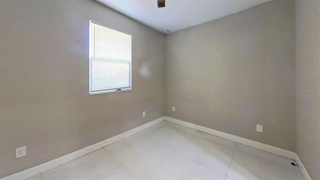 An empty bedroom features light gray walls, white baseboards, tiled flooring, and a single window — 2726 MIAMI TERRACE UNIT B, KISSIMMEE, FL