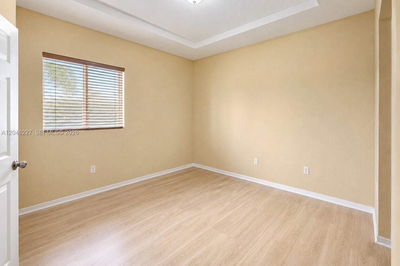 An empty room features light-colored wood flooring, beige walls, and a window with blinds — 8526 NW 107th Psge # 40, Doral FL 33178, DORAL, FL
