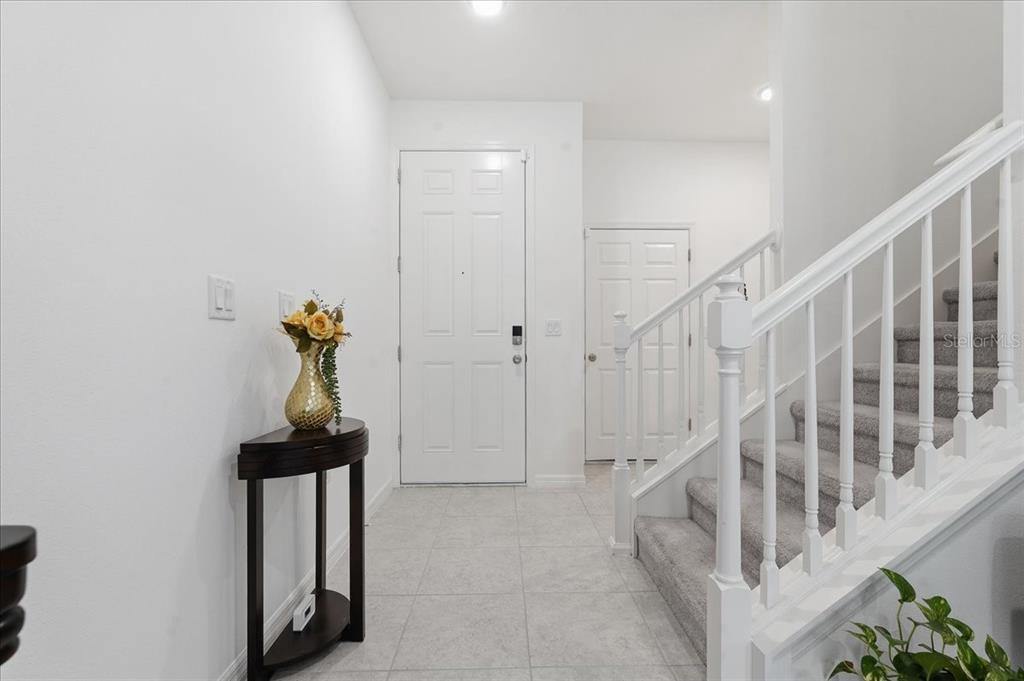 An entryway features a white front door, a staircase with carpeted steps, and tile flooring — 34179 CINDER WAY, WESLEY CHAPEL, FL