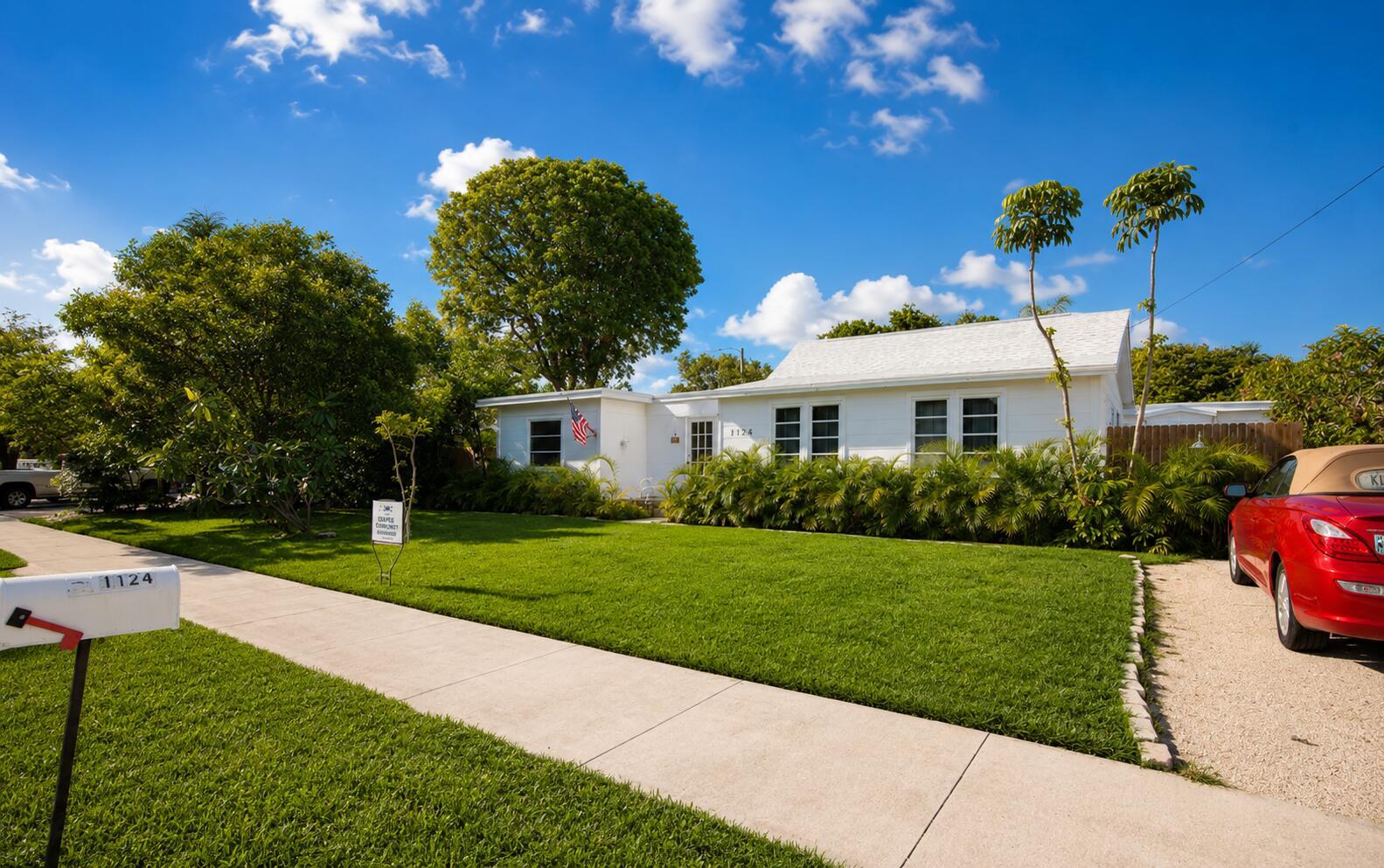 A white single-story house with a green lawn and a red car parked in front — 1124 18th Avenue N # 1, FL 33460, FL