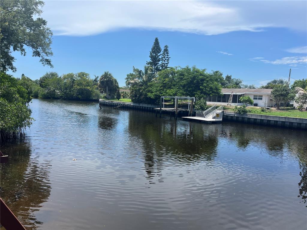 A view of a narrow canal lined with trees, palm trees, and a residential seawall — 9105 TUDOR DRIVE UNIT F103, TAMPA, FL