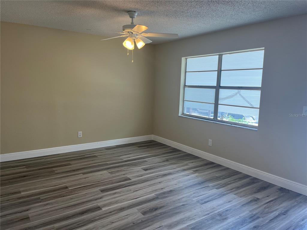An empty bedroom features light-colored walls, a ceiling fan, and gray wood-look flooring — 9105 TUDOR DRIVE UNIT F103, TAMPA, FL