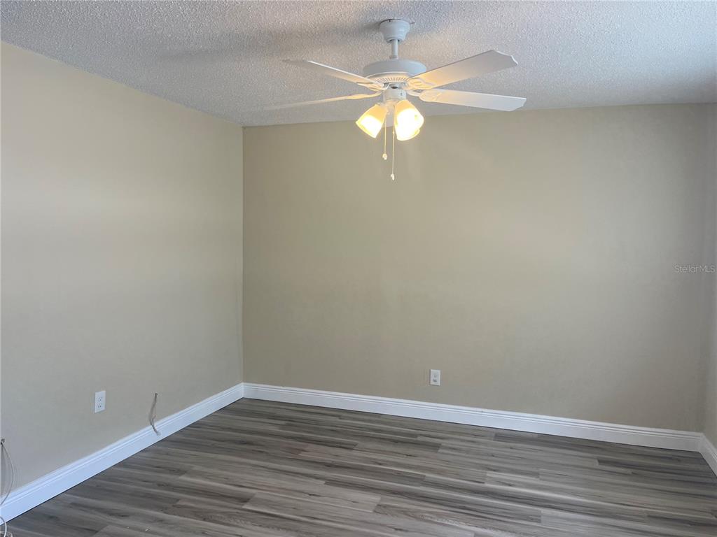 An empty room features light beige walls, gray wood-look flooring, and a ceiling fan — 9105 TUDOR DRIVE UNIT F103, TAMPA, FL