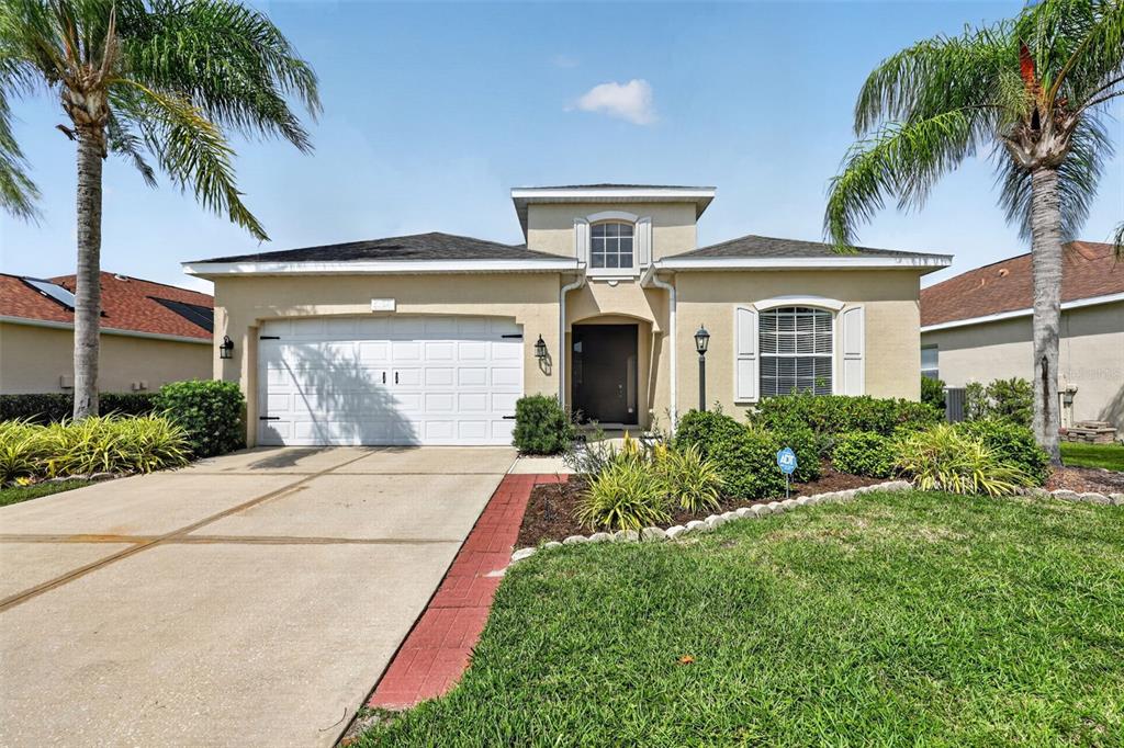 A single-story house with a two-car garage, beige stucco exterior, and two palm trees — 5328 LEXINGTON DRIVE, PARRISH, FL