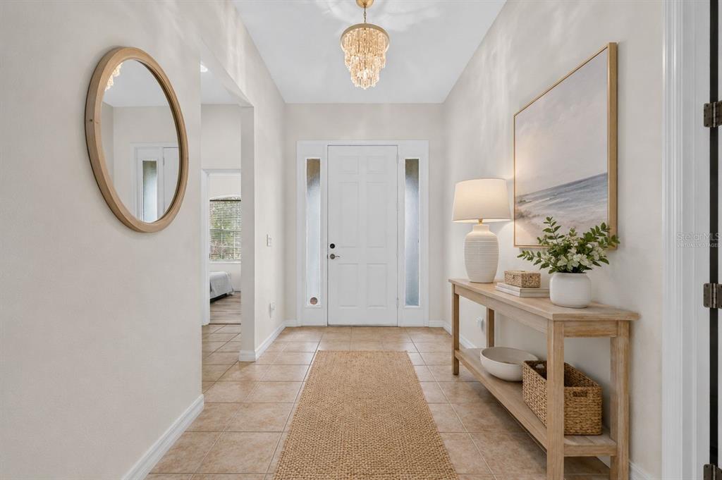 A bright entryway features tile flooring, a console table, a chandelier, and a front door — 5328 LEXINGTON DRIVE, PARRISH, FL