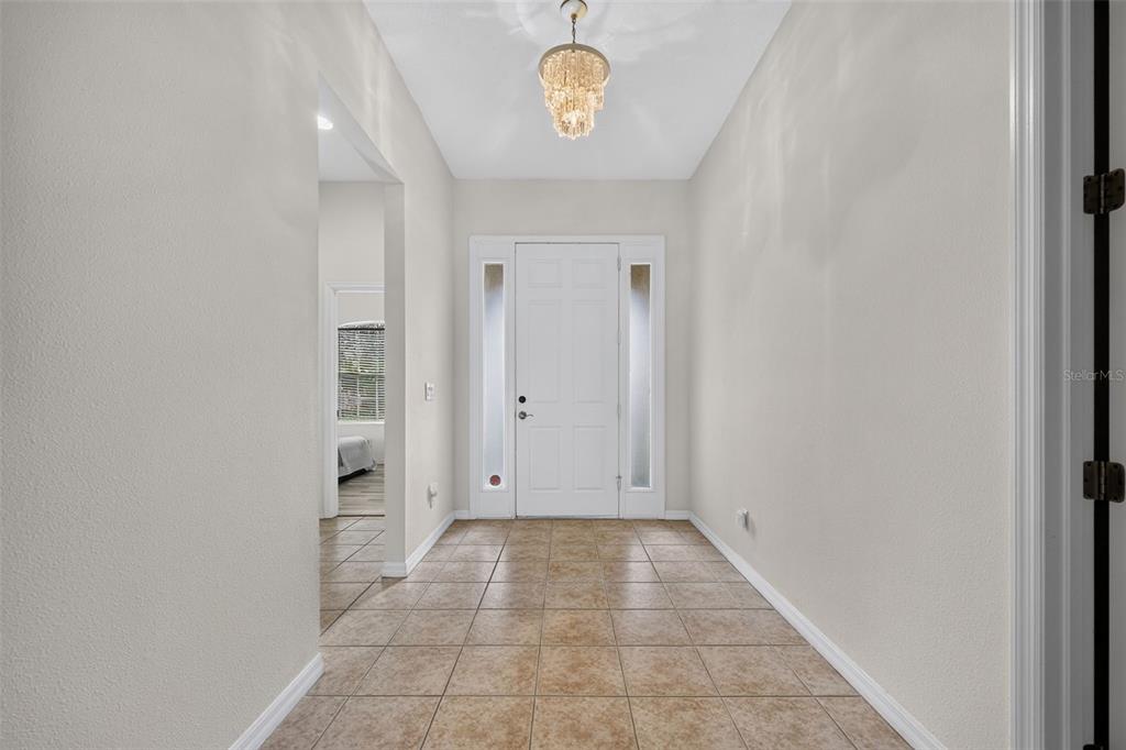 A tiled entryway features a white front door with sidelights and a crystal chandelier — 5328 LEXINGTON DRIVE, PARRISH, FL