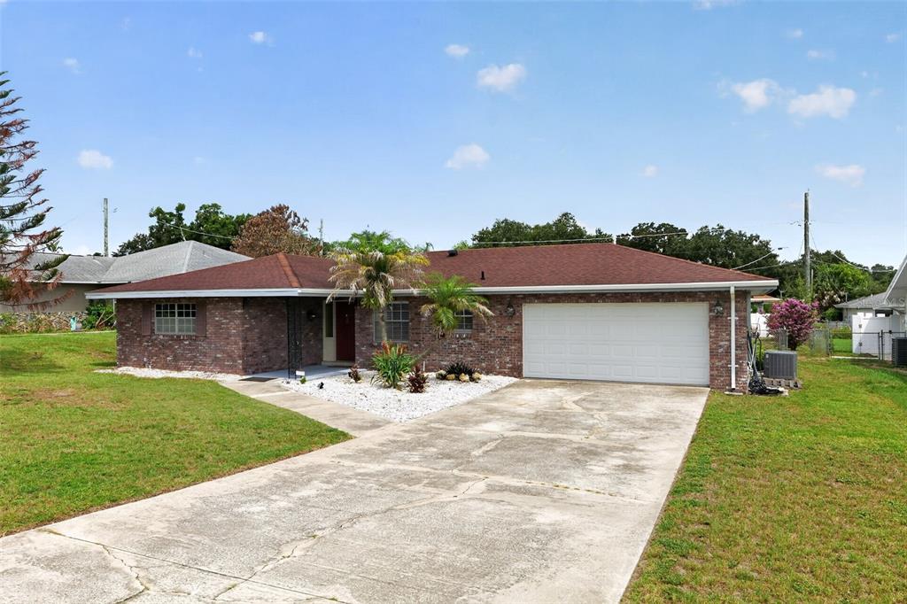 A single-story brick house with a red roof, two-car garage, and a concrete driveway — 516 ALACHUA DRIVE, WINTER HAVEN, FL