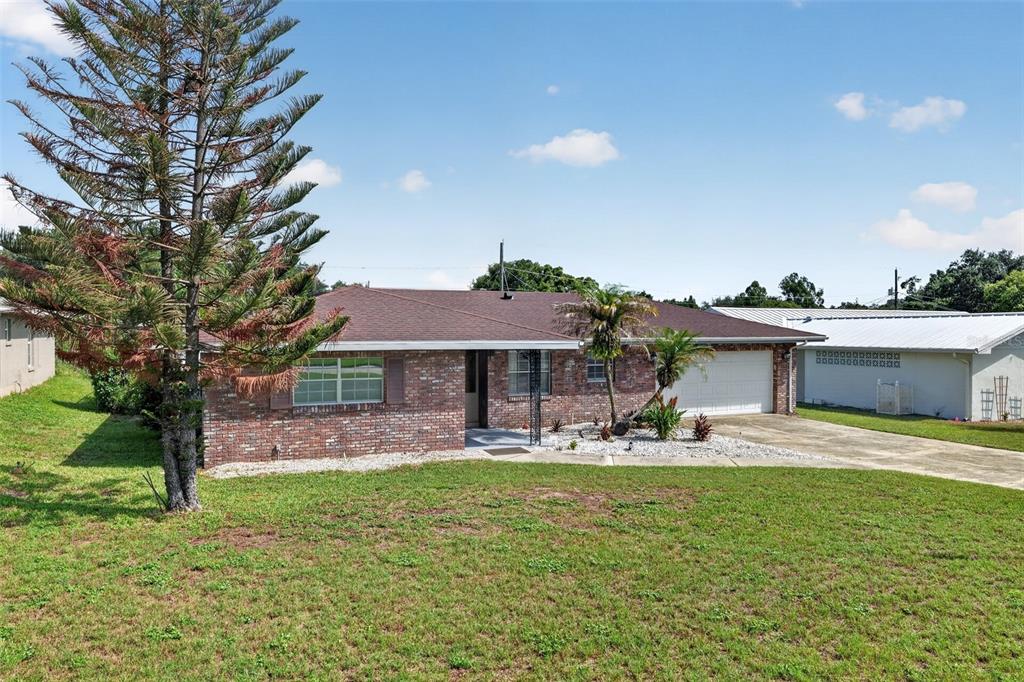 A single-story brick house with a two-car garage and a large pine tree — 516 ALACHUA DRIVE, WINTER HAVEN, FL