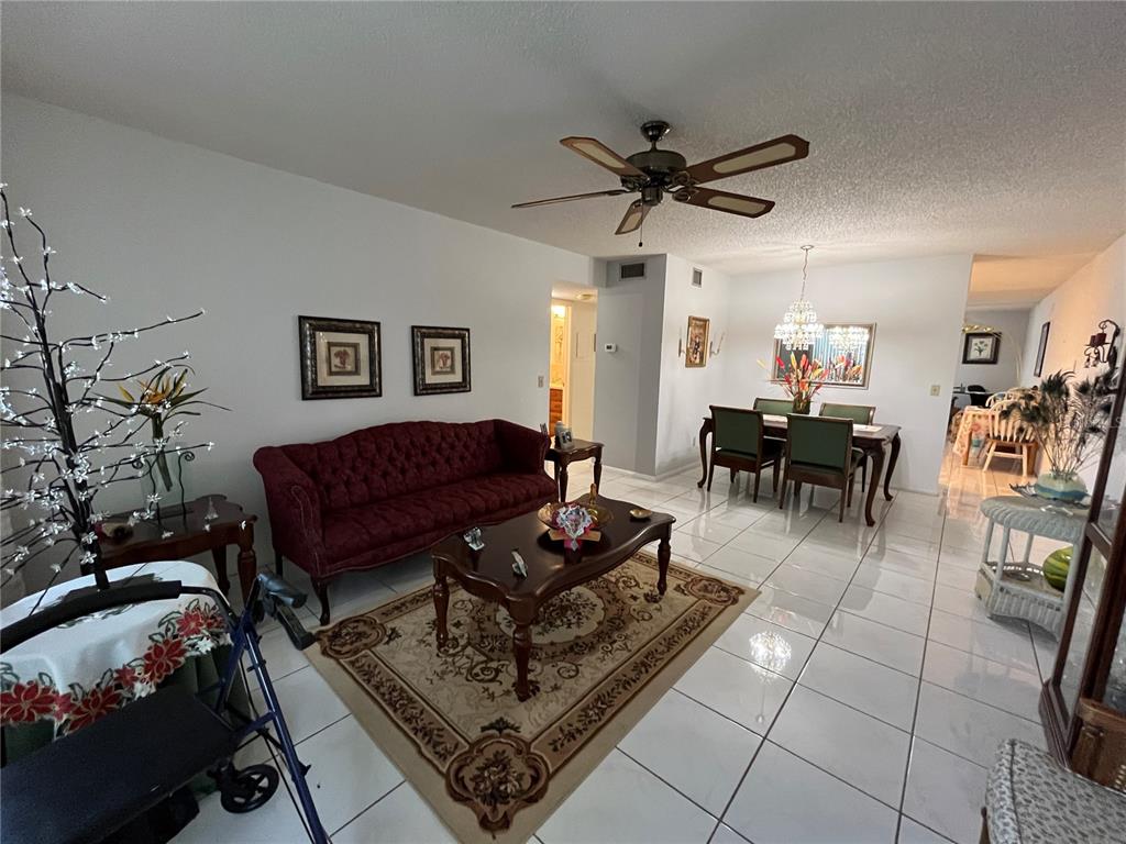 A living and dining area with white tile floors, a red sofa, and a ceiling fan — 2253 NORWEGIAN DRIVE UNIT 33, CLEARWATER, FL