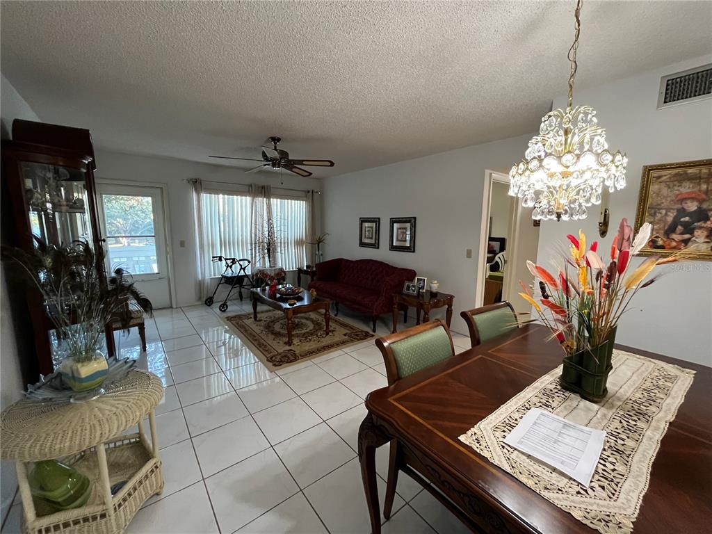 A dining area with a crystal chandelier overlooks a living room featuring tile floors — 2253 NORWEGIAN DRIVE UNIT 33, CLEARWATER, FL