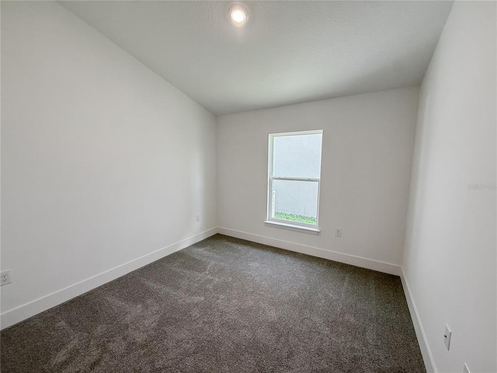 An empty bedroom features white walls, light-colored carpet, and a single window — 270 VERNY GROVE LANE, LEESBURG, FL