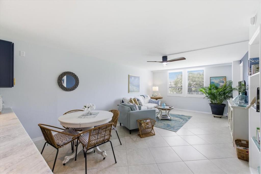 An open-concept living and dining area features tile flooring, a ceiling fan, and white walls — 2621 COVE CAY DRIVE UNIT 302, CLEARWATER, FL