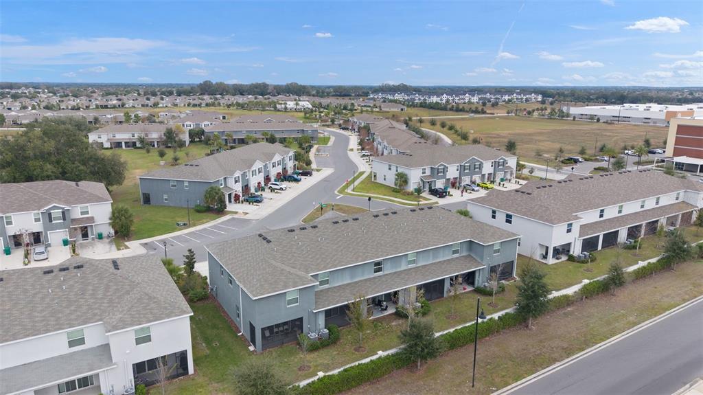 An aerial view shows several multi-story townhomes with gray siding and shingled roofs — 5349 PINECONE COURT, WILDWOOD, FL