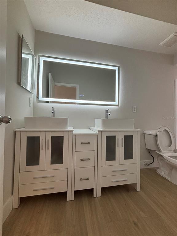 A bathroom features a double vanity with vessel sinks, a backlit mirror, and light flooring — 12208 WILD IRIS WAY UNIT 112, ORLANDO, FL