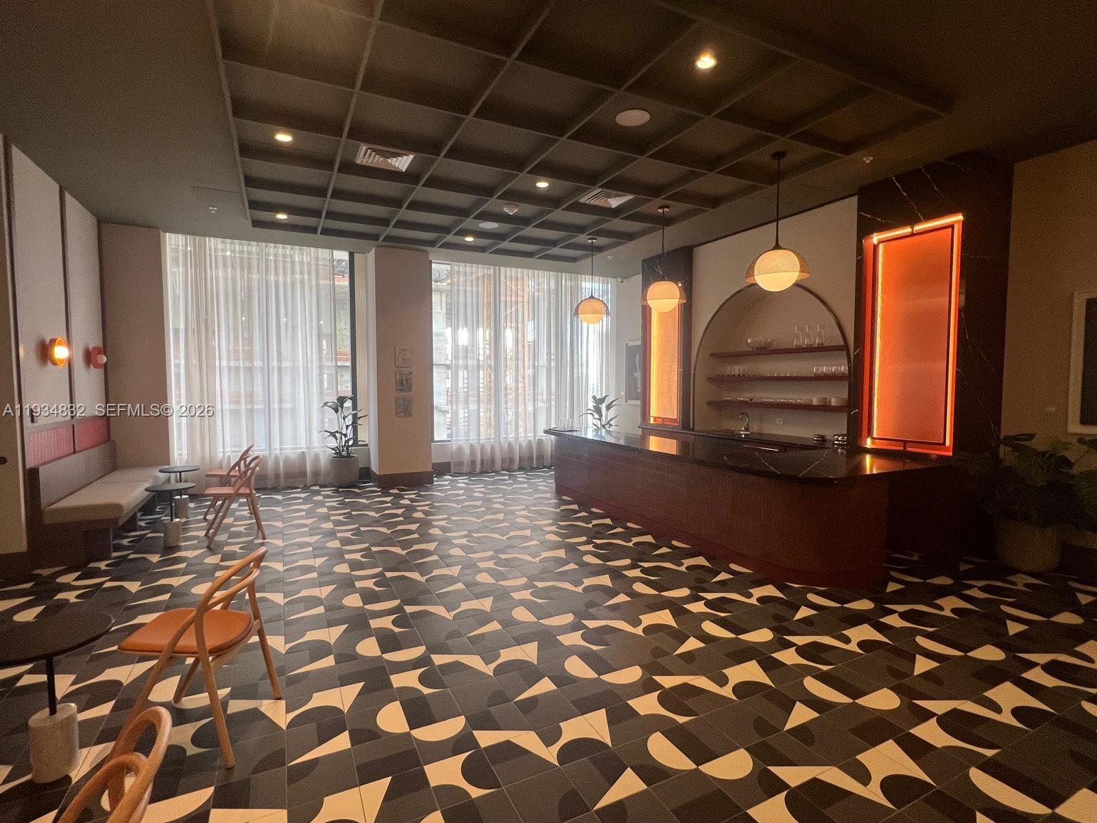 A modern lounge features a bar with arched shelving, patterned tile flooring, and grid ceilings — 11 NE 6 ST # 2709, Miami FL 33132, MIAMI, FL