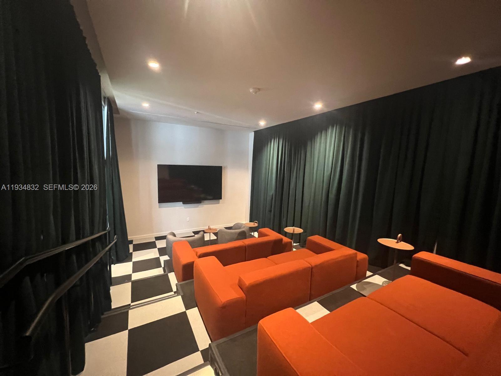 A home theater features orange modular seating, a black-and-white checkered floor, and dark curtains — 11 NE 6 ST # 2709, Miami FL 33132, MIAMI, FL
