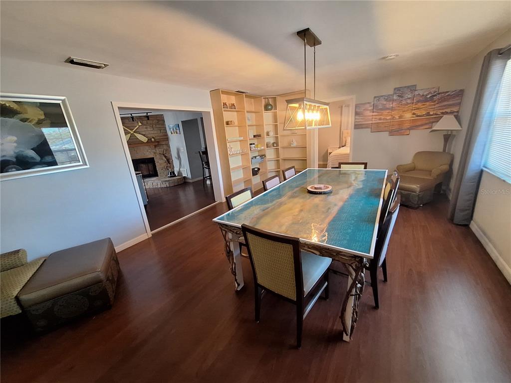 A dining room features a large resin-topped table, built-in shelving, and wood-look flooring — 505 N HIGHLAND AVENUE, CLEARWATER, FL