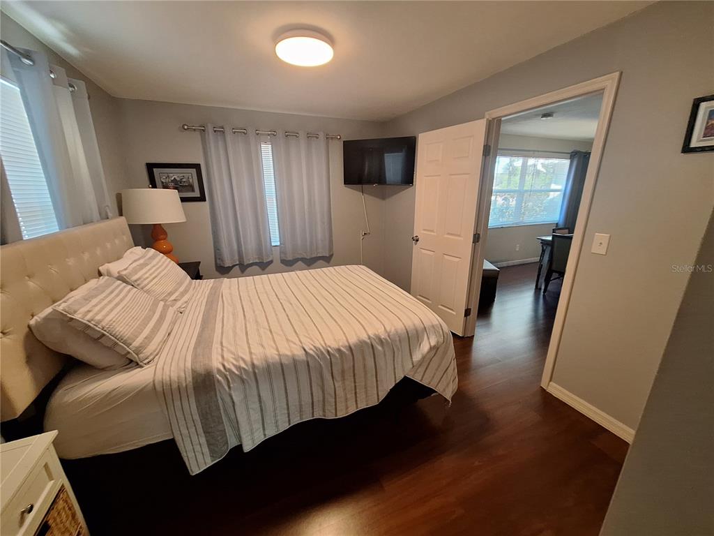 A bedroom features a tufted headboard, striped bedding, dark wood flooring, and a wall-mounted television — 505 N HIGHLAND AVENUE, CLEARWATER, FL