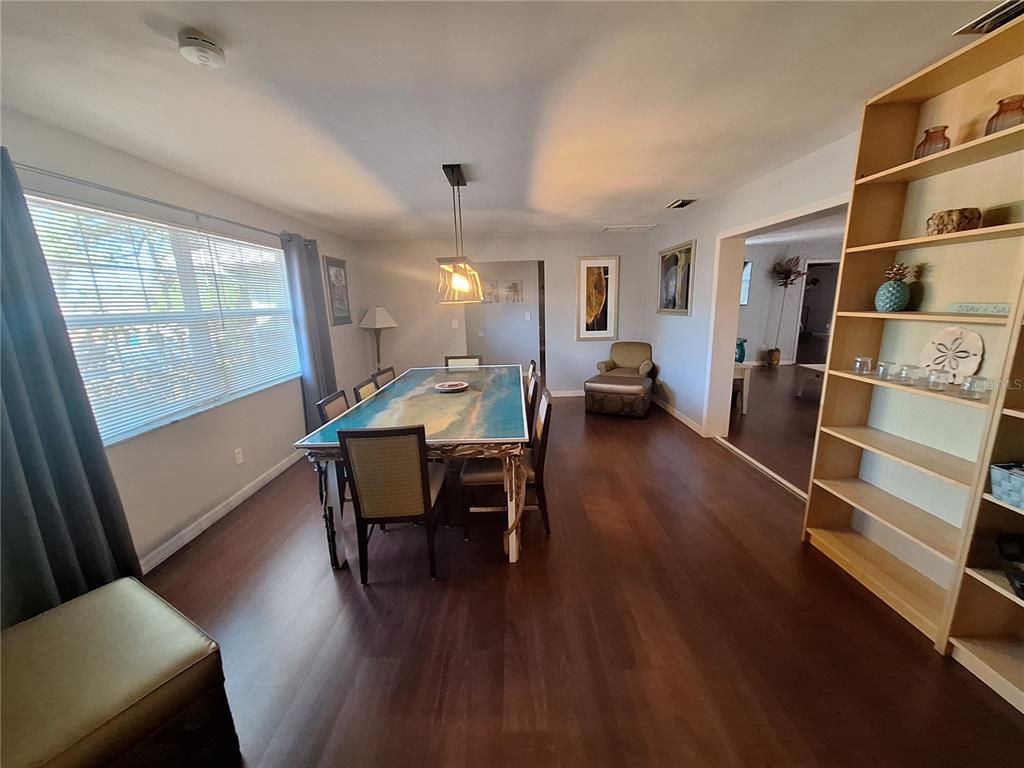 A dining room features a blue-topped table, wood flooring, and an open wooden bookshelf — 505 N HIGHLAND AVENUE, CLEARWATER, FL