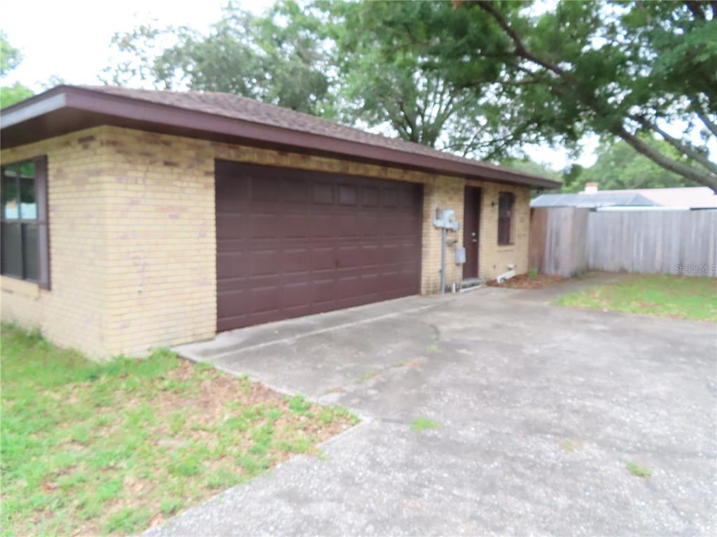 A brick exterior of a house featuring a garage door, a side door, and driveway — 2016 AMESBURY DRIVE, AUBURNDALE, FL