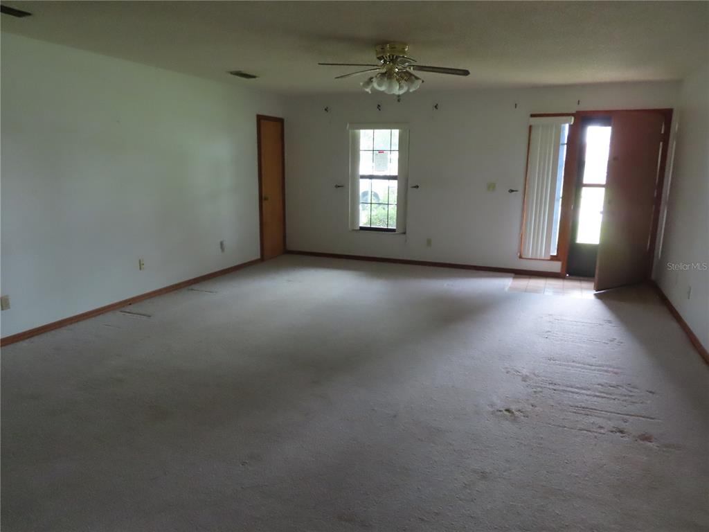 An empty room features beige carpeting, white walls, a ceiling fan, and an open door — 2016 AMESBURY DRIVE, AUBURNDALE, FL
