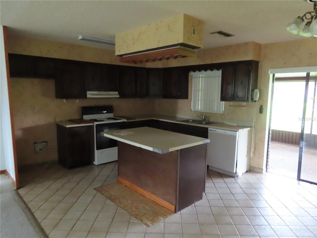 A kitchen with dark wood cabinets, a central island, and light-colored tile flooring — 2016 AMESBURY DRIVE, AUBURNDALE, FL