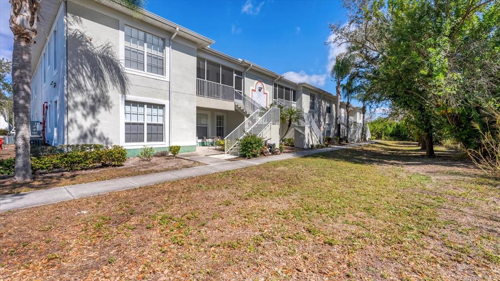 A two-story apartment building features a concrete walkway, exterior staircases, and screened-in balconies — 2628 RIVER PRESERVE COURT UNIT 2628, BRADENTON, FL